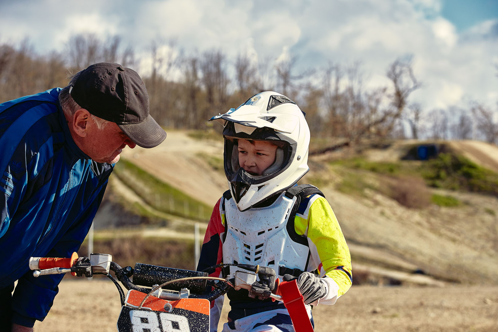 kids riding at motobike, junior competition on motorcycle. Coach gives instructions to his young rider