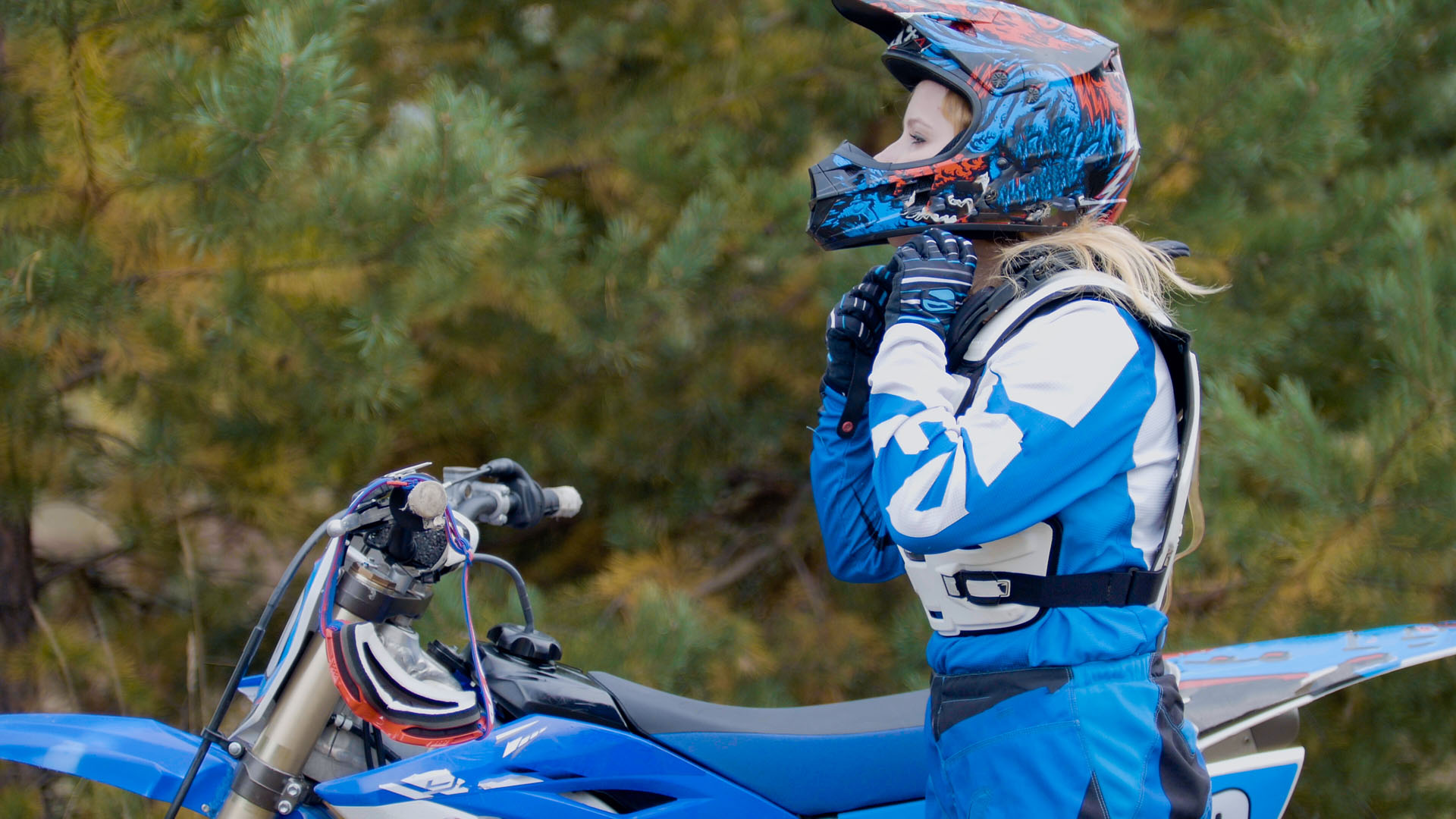 Girl Bike wears a helmet MX moto cross racing rider on a dirt motorcycle